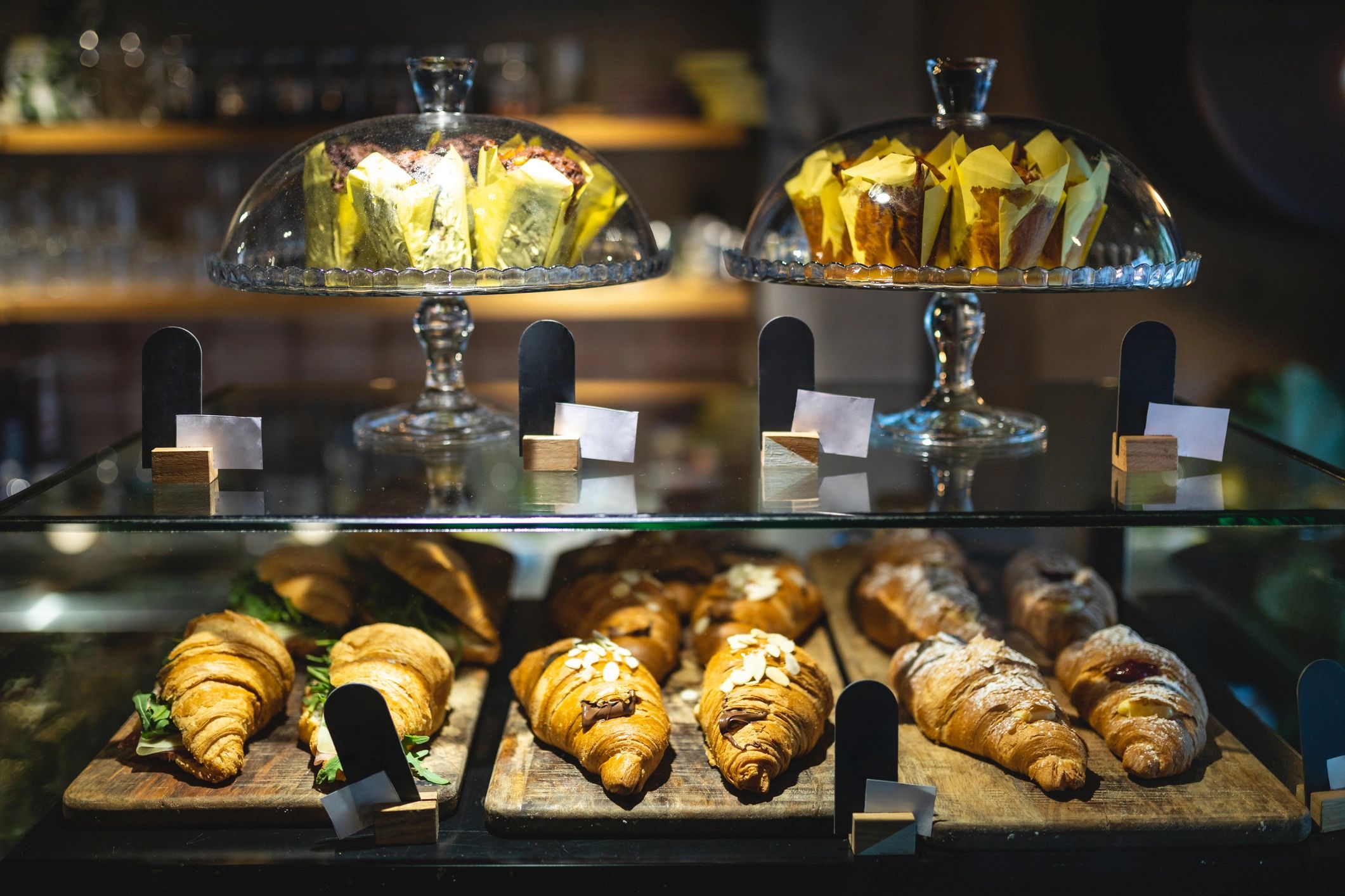 Croissant sandwiches and chocolate sweets under a glass bell