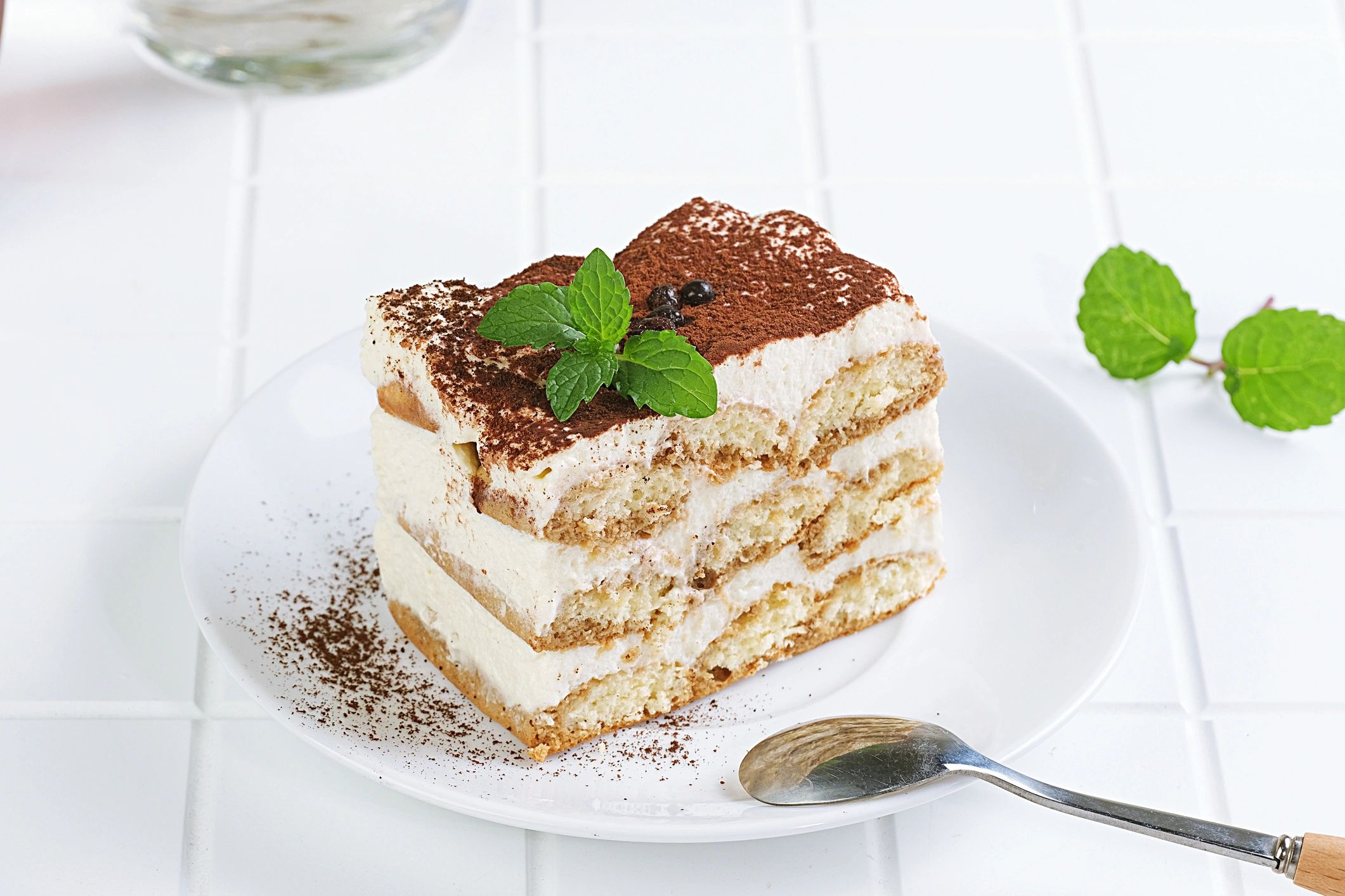 Tiramisu cake slice on a plate with spoon