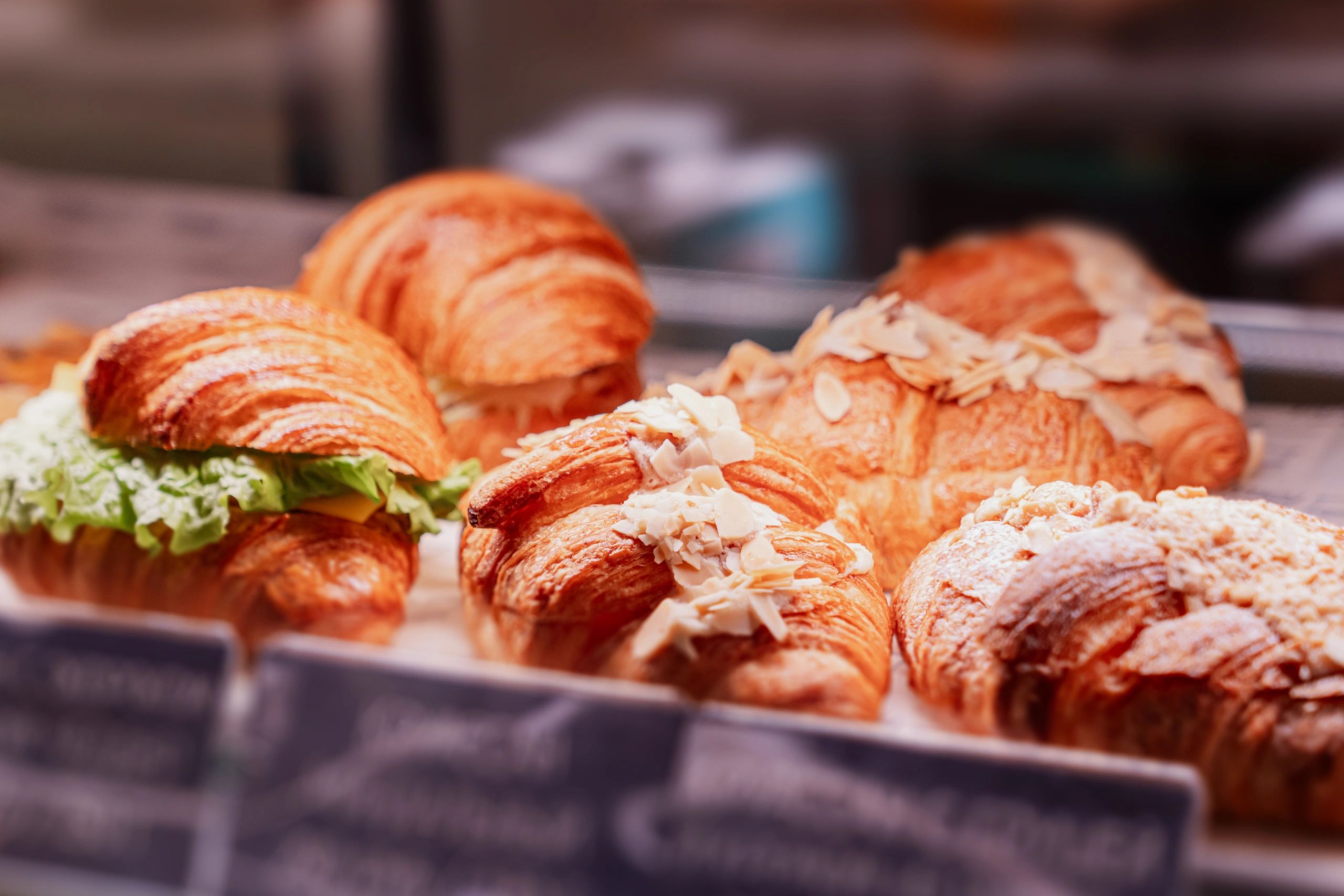 Fresh golden croissants with almond flakes in a bakery case